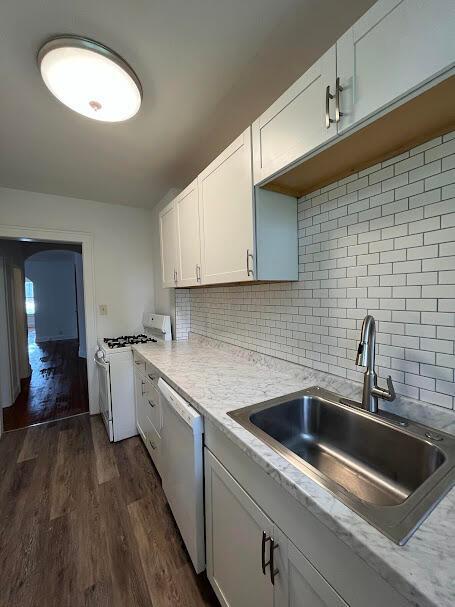 kitchen with sink, white appliances, dark wood-type flooring, white cabinetry, and tasteful backsplash