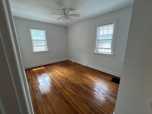 spare room with plenty of natural light, dark hardwood / wood-style floors, and ceiling fan