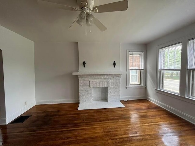 unfurnished living room featuring a fireplace, dark wood-type flooring, and ceiling fan