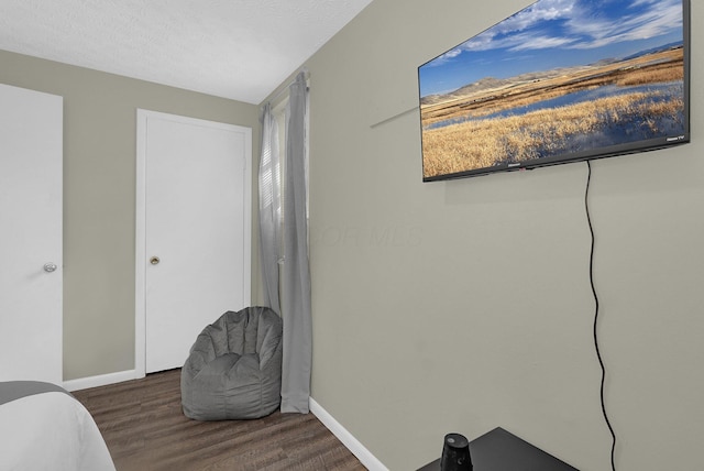 bedroom featuring a textured ceiling and dark hardwood / wood-style flooring