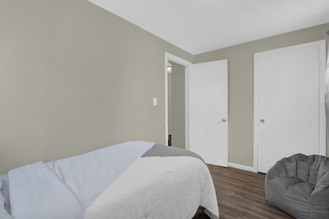 bedroom with dark hardwood / wood-style flooring and a textured ceiling