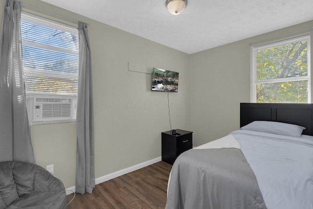 bedroom featuring cooling unit, dark hardwood / wood-style floors, and a textured ceiling