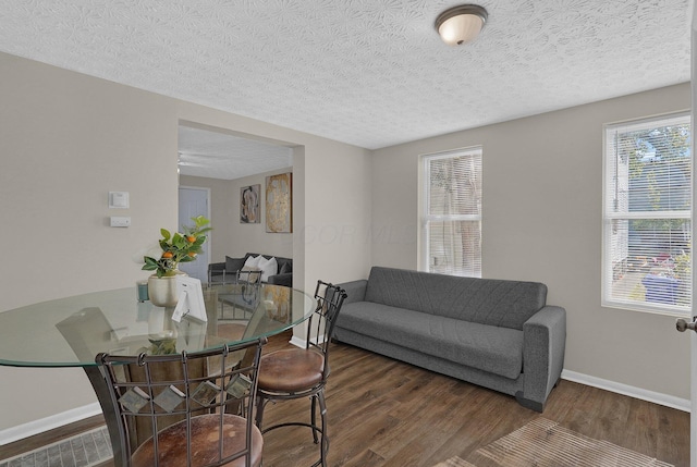 dining space with dark hardwood / wood-style floors and a textured ceiling