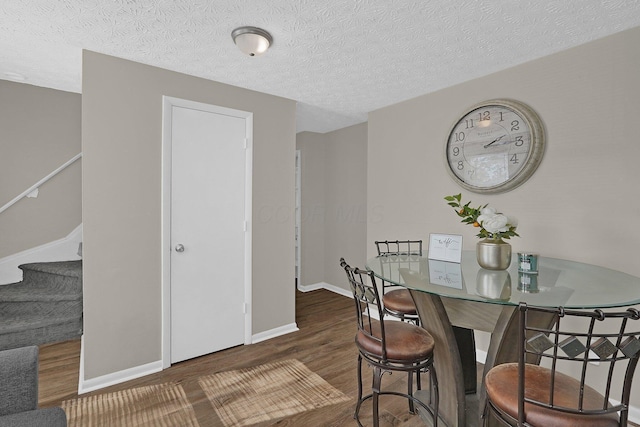 dining area with dark hardwood / wood-style floors and a textured ceiling