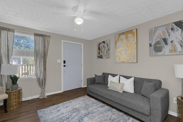 living room featuring ceiling fan, dark wood-type flooring, and a textured ceiling