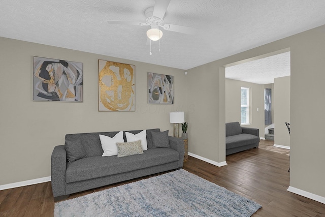 living room with ceiling fan, dark hardwood / wood-style floors, and a textured ceiling