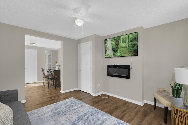 living room with ceiling fan, dark hardwood / wood-style flooring, and a textured ceiling