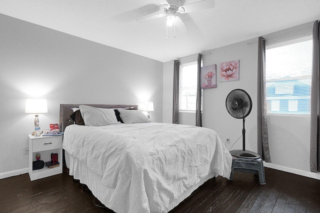 bedroom with a textured ceiling, dark wood-style flooring, and baseboards