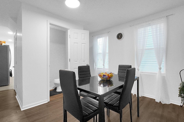 dining room featuring dark wood-type flooring, baseboards, and a textured ceiling