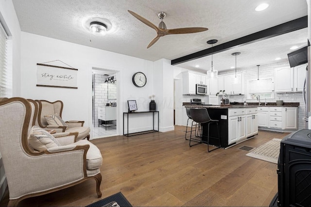 living room featuring dark hardwood / wood-style floors, a textured ceiling, and beam ceiling