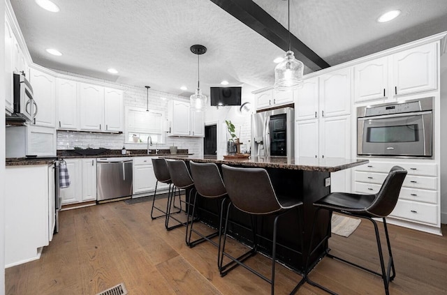 kitchen featuring appliances with stainless steel finishes, a center island, white cabinets, and a kitchen bar