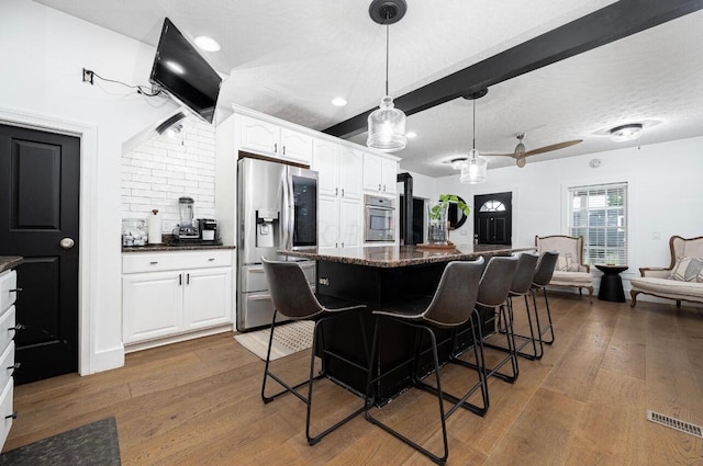 kitchen featuring stainless steel appliances, white cabinetry, dark wood-type flooring, and a kitchen breakfast bar