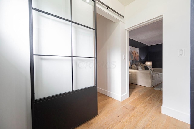 corridor with a barn door and light wood-type flooring