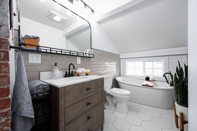 bathroom with tile walls, a bathing tub, vanity, vaulted ceiling, and toilet