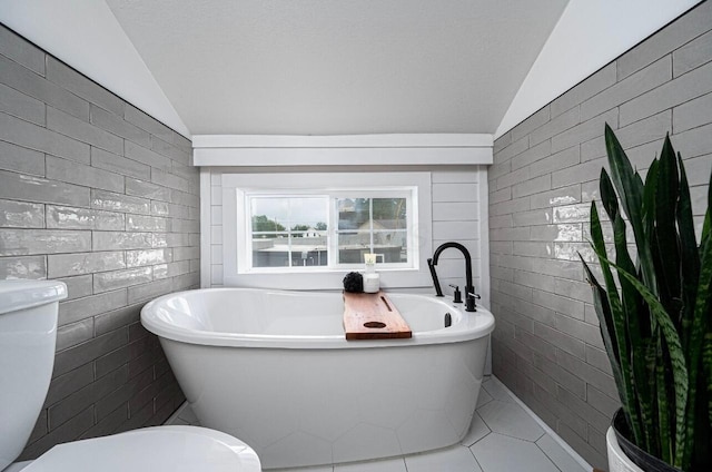 bathroom featuring lofted ceiling, a washtub, and tile walls