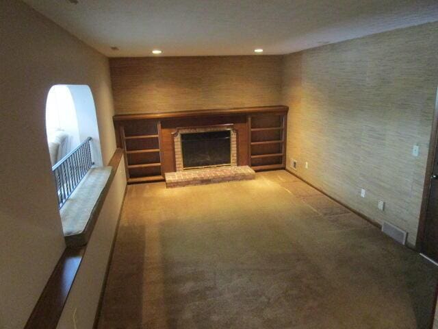 unfurnished living room featuring a brick fireplace and carpet floors