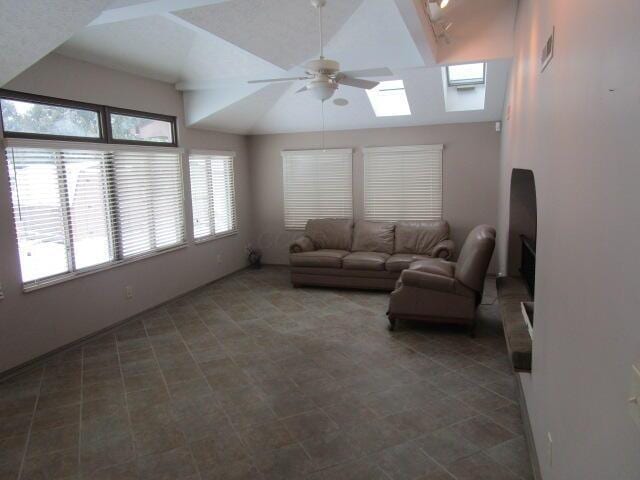 living room with lofted ceiling with skylight and ceiling fan