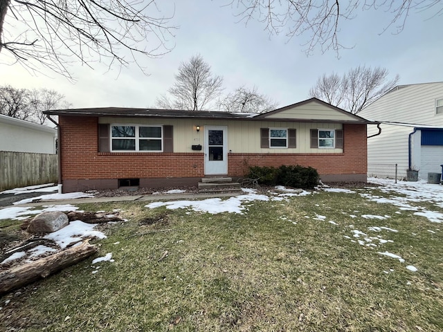 single story home with entry steps, brick siding, fence, and a lawn