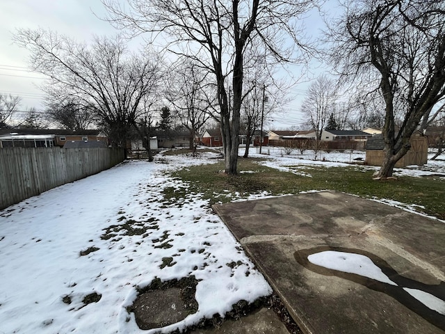 yard layered in snow featuring fence and an outbuilding