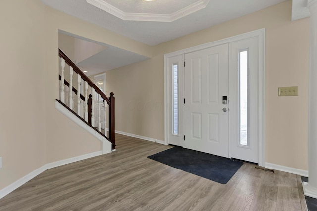 entryway with a raised ceiling, visible vents, baseboards, and wood finished floors