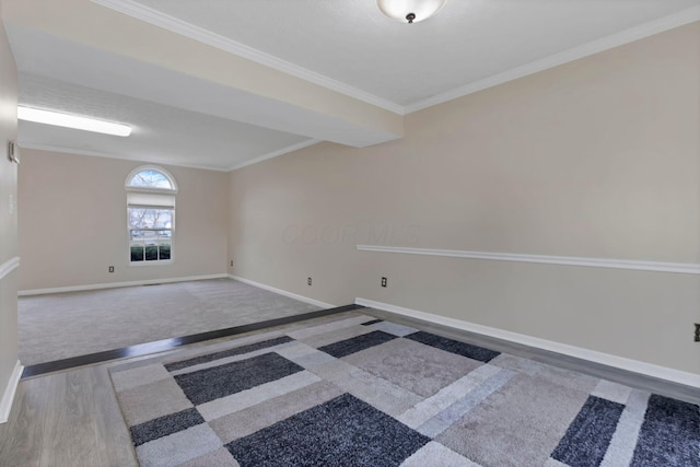 spare room featuring ornamental molding, baseboards, and wood finished floors