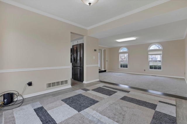 spare room featuring baseboards, visible vents, crown molding, and wood finished floors