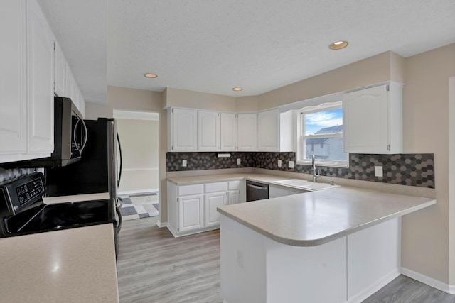 kitchen featuring a peninsula, white cabinetry, stainless steel appliances, and a sink