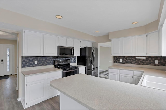 kitchen featuring a peninsula, white cabinetry, appliances with stainless steel finishes, and backsplash