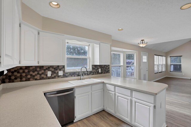 kitchen with light wood-style floors, white cabinets, a sink, dishwasher, and a peninsula