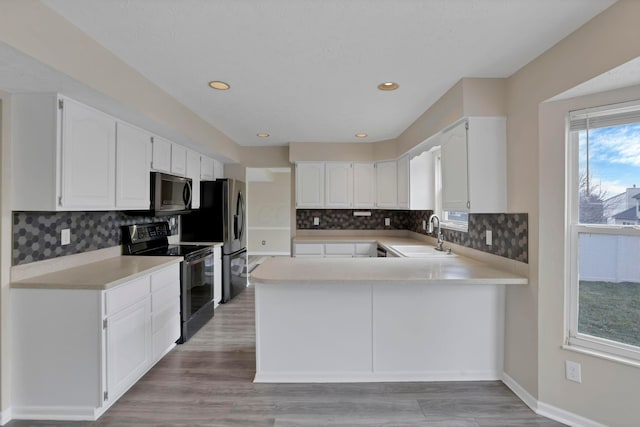 kitchen with stainless steel appliances, light countertops, a sink, and a peninsula