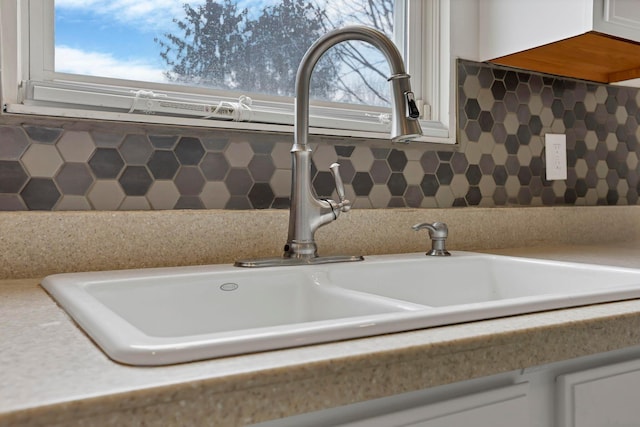 details with light countertops, backsplash, a sink, and white cabinets