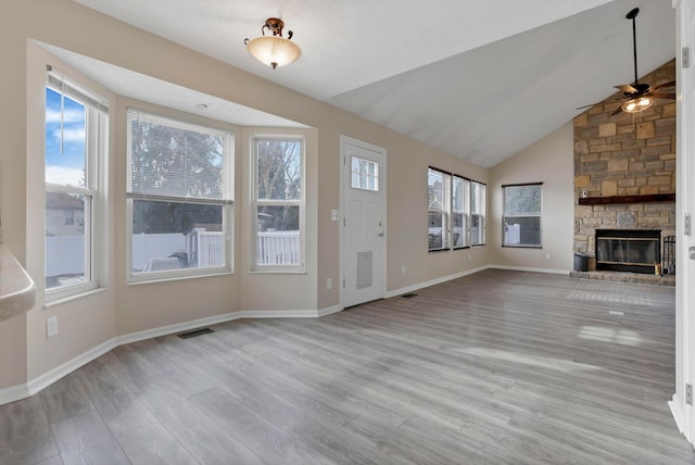 unfurnished living room featuring visible vents, a stone fireplace, baseboards, and wood finished floors