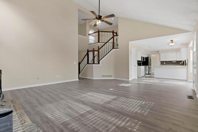 unfurnished living room with ceiling fan, stairway, wood finished floors, and visible vents