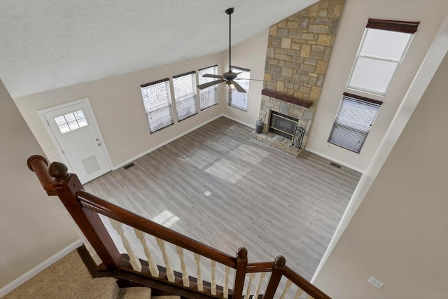 living room featuring plenty of natural light, a fireplace, baseboards, and a ceiling fan