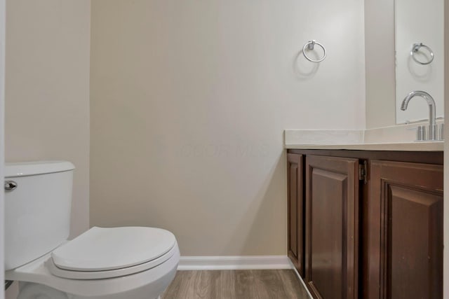 bathroom featuring toilet, vanity, baseboards, and wood finished floors