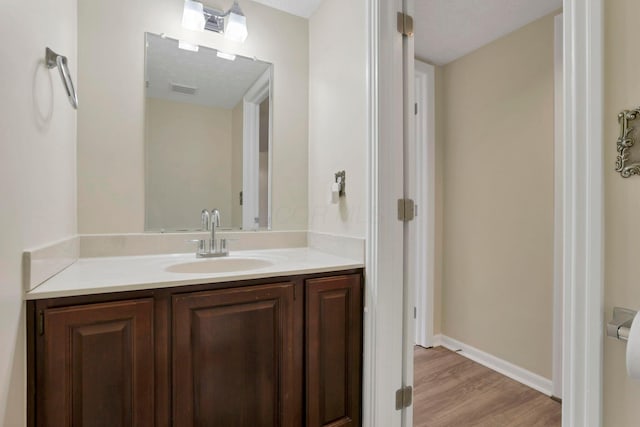 bathroom featuring visible vents, vanity, baseboards, and wood finished floors