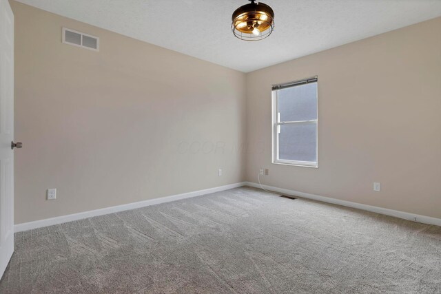 empty room featuring baseboards, visible vents, a textured ceiling, and carpet flooring