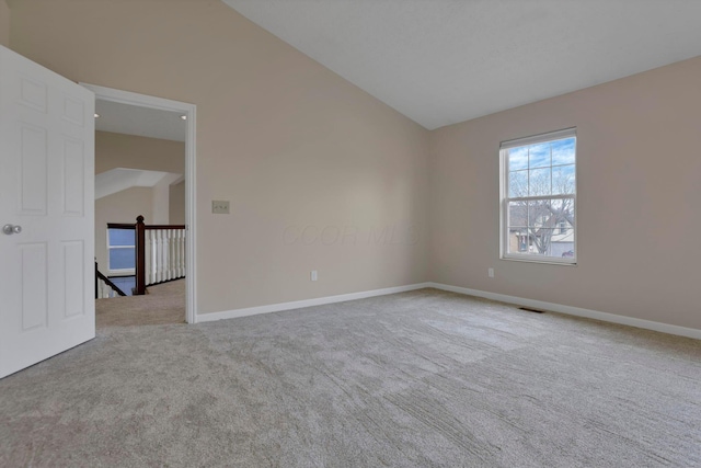 carpeted spare room featuring lofted ceiling, visible vents, and baseboards