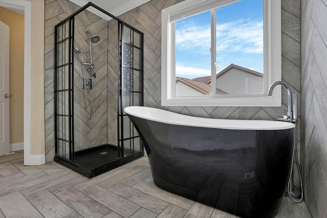 full bath featuring a stall shower, a freestanding tub, and tile walls