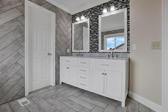 bathroom with double vanity, visible vents, a sink, crown molding, and tile walls