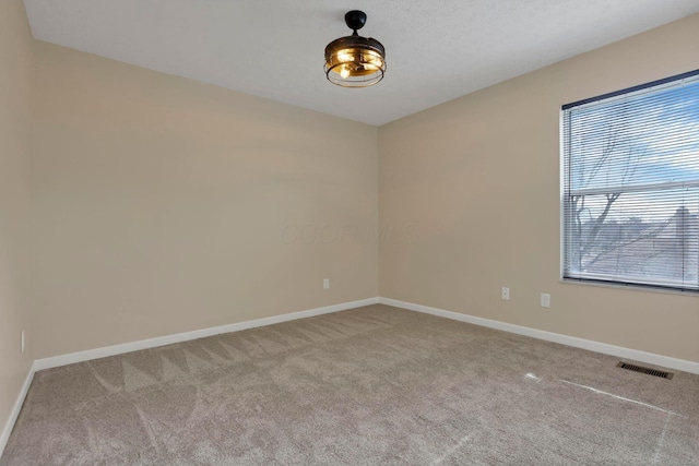 carpeted empty room featuring visible vents and baseboards