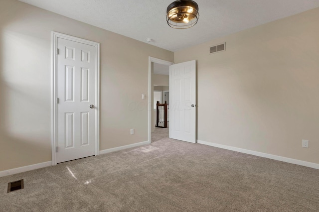 unfurnished bedroom with carpet, visible vents, and baseboards