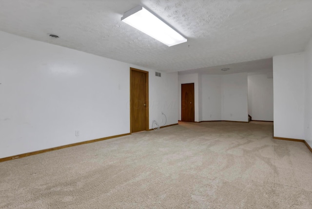 carpeted spare room featuring a textured ceiling, visible vents, and baseboards