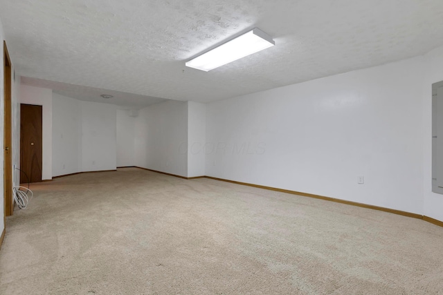 carpeted spare room featuring baseboards and a textured ceiling