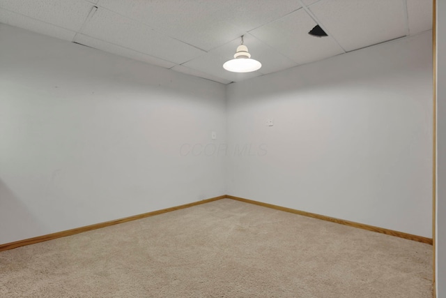 spare room featuring carpet flooring, a paneled ceiling, and baseboards