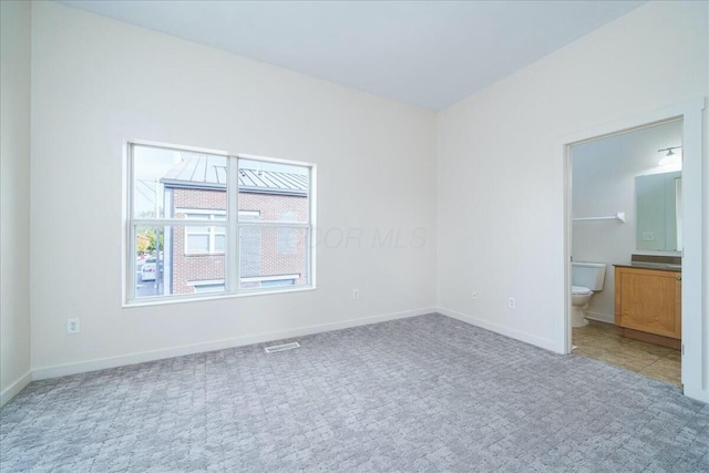 unfurnished bedroom with connected bathroom and carpet floors