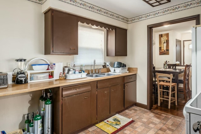 kitchen featuring dark brown cabinets, sink, and white appliances