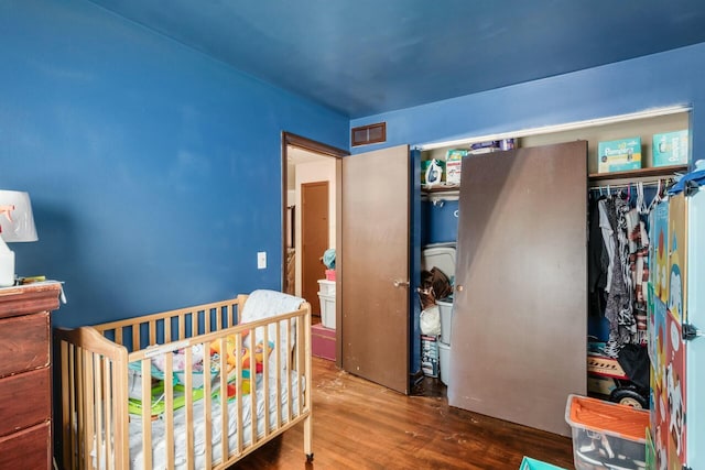 bedroom with hardwood / wood-style flooring, a nursery area, and a closet