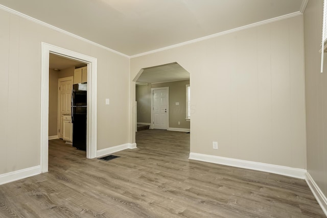 empty room featuring ornamental molding and light wood-type flooring