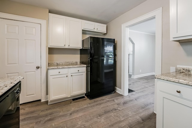 kitchen with light stone counters, white cabinets, light hardwood / wood-style flooring, and black appliances